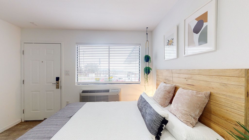 A bedroom with a bed, pillows, and a window with blinds.