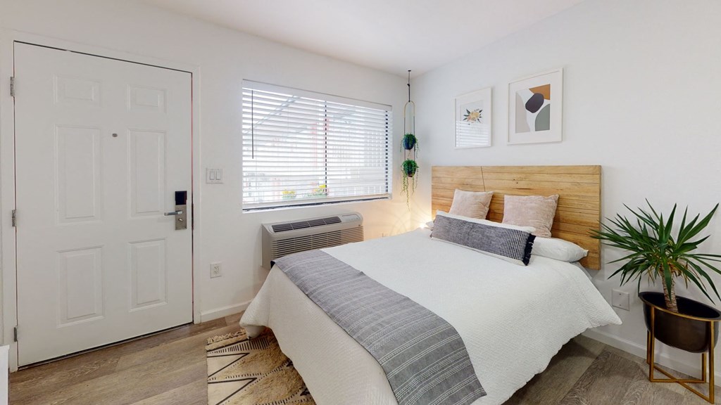 A bedroom with a bed, a chair, and a plant.