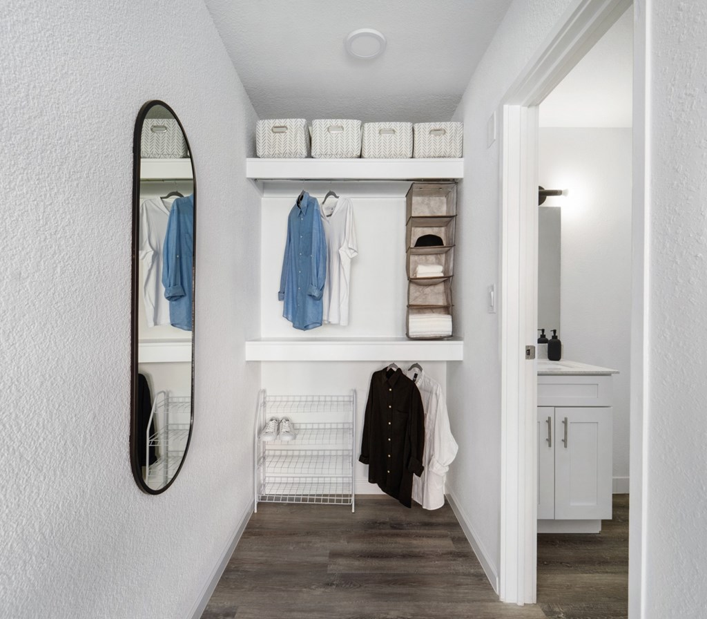A hallway with a mirror, coat rack, and shelves.