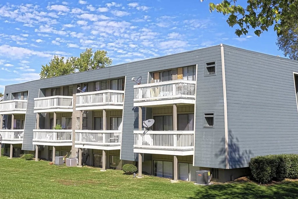 A grey apartment building with balconies and a blue sky in the background.