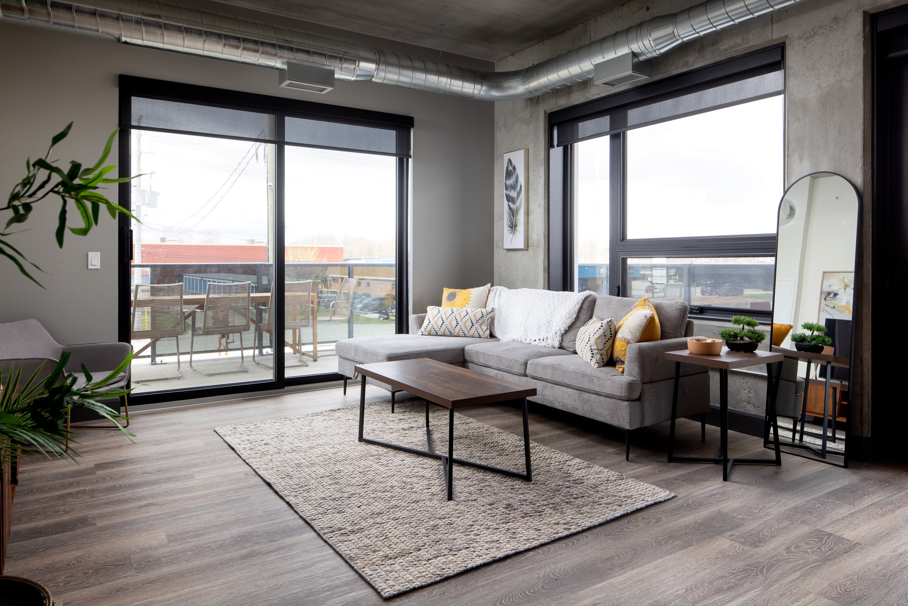 A living room with a grey sofa and a coffee table in front of a large window.
