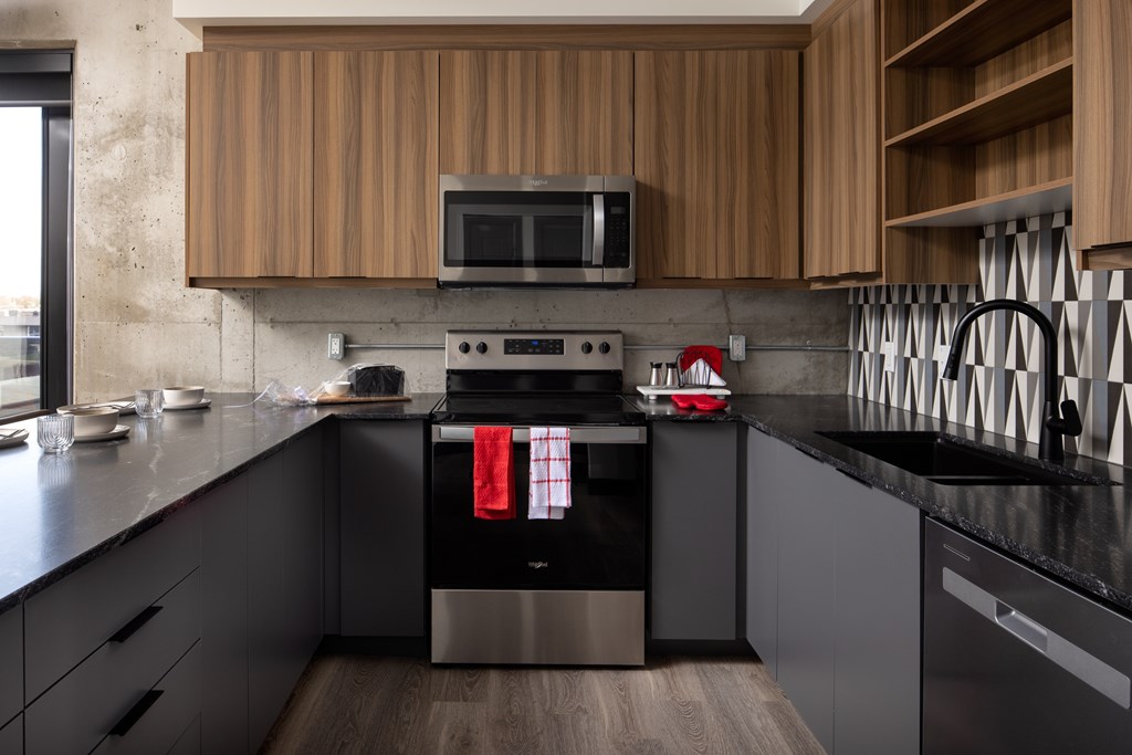 A modern kitchen with a black countertop and stainless steel appliances.at Damask, Windsor, ON