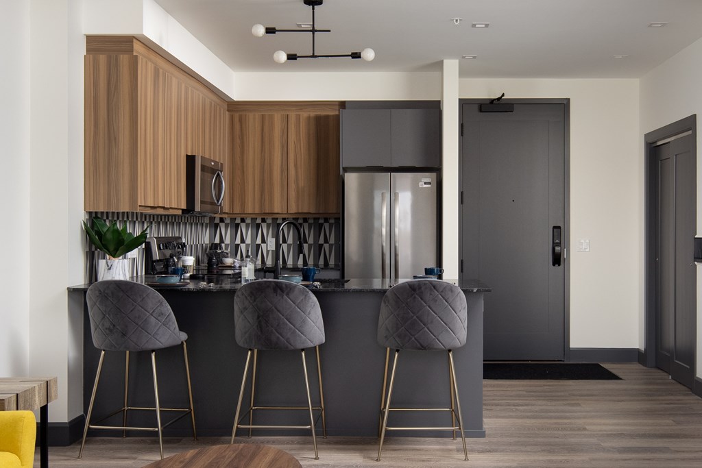 A modern kitchen featuring wood grain upper cabinets, dark stone countertops and stainless steel appliances at Damask, Windsor