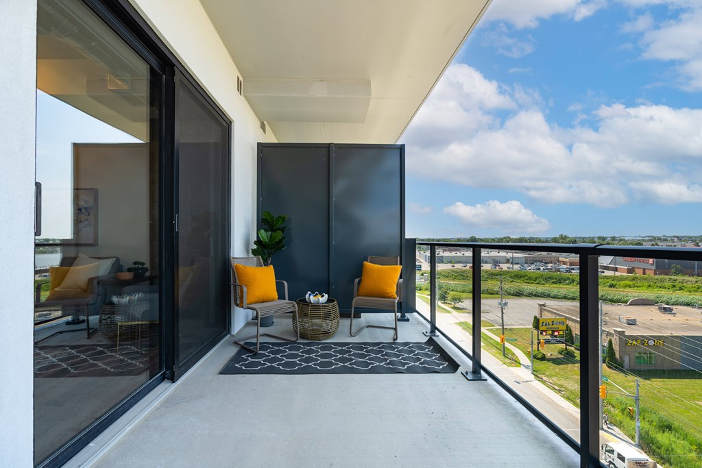 A balcony with a chair and a table with a plant on it.