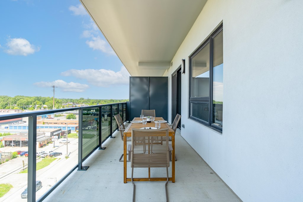 A balcony with a table and chairs overlooking a street.