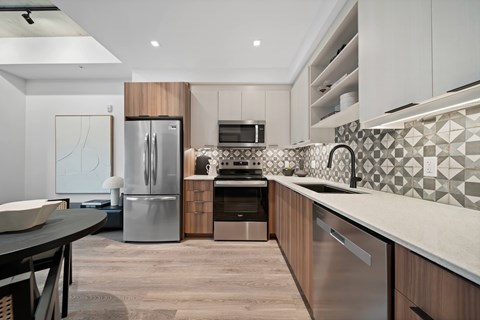 A modern kitchen with a stainless steel refrigerator and a black and white tiled backsplash