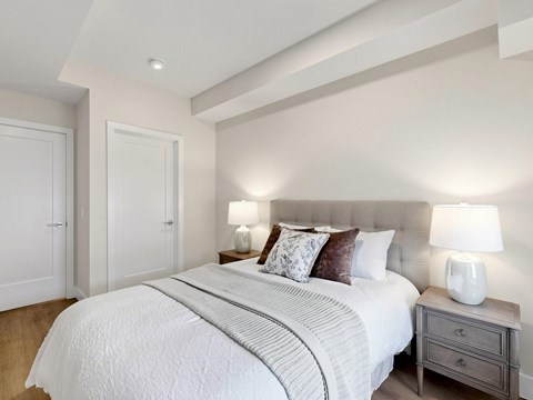 A bedroom with a large bed and two lamps.
