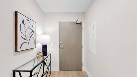 A hallway with a glass table and a painting on the wall.