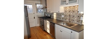 A kitchen with white cabinets and a tile backsplash.