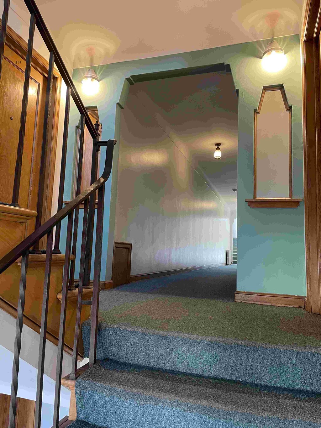 A staircase with a carpeted runner and a mirror on the wall.
