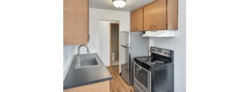 A kitchen with a stove, sink, and cabinets.