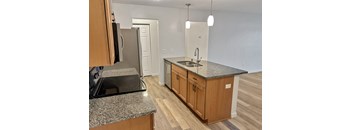 A kitchen with granite countertops and wooden cabinets.