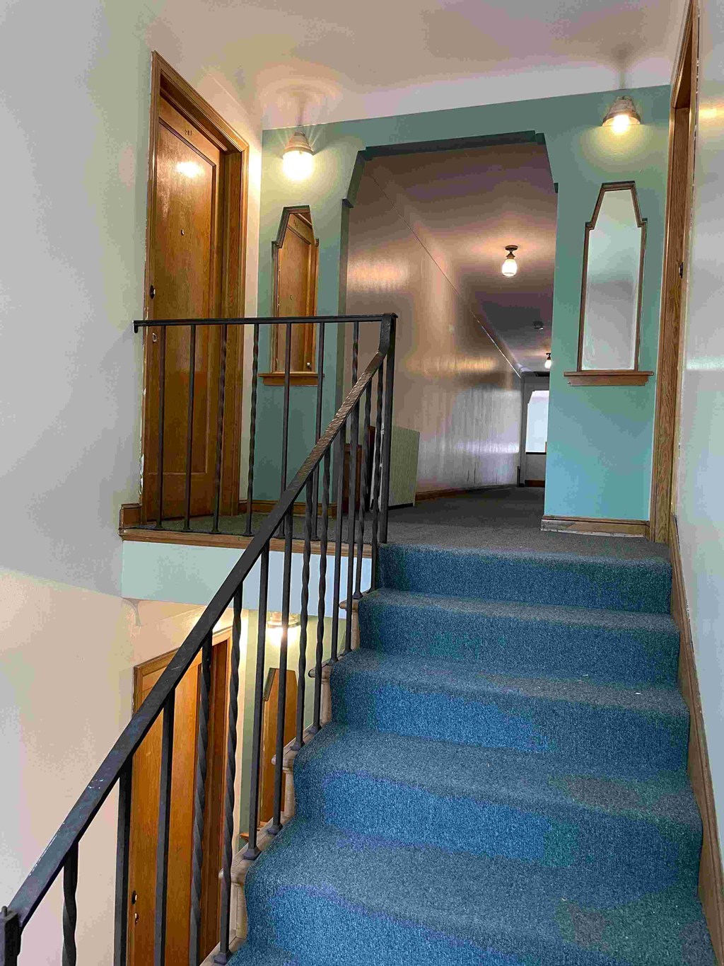 A staircase with a blue carpeted runner and wooden balusters.