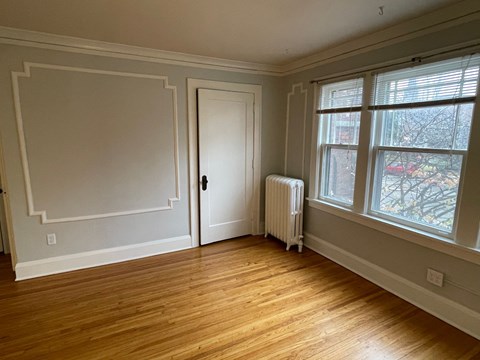 A room with a door, a window, and a radiator.