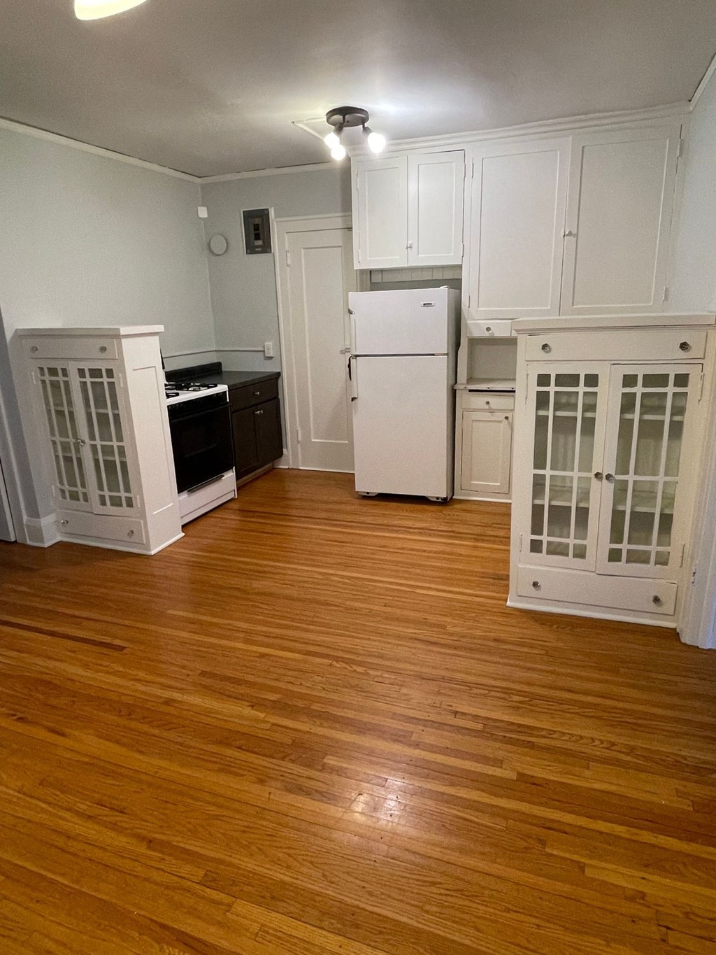 A kitchen with white cabinets and a white fridge.