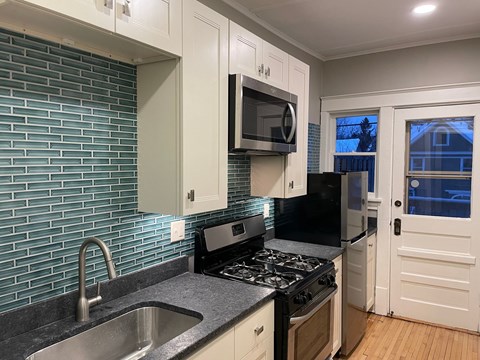 A kitchen with a black stove top oven and a black microwave above it.