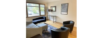 A living room with a black chair and a grey sofa.