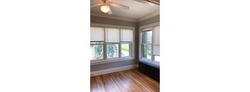 A room with a ceiling fan and a window with blinds.