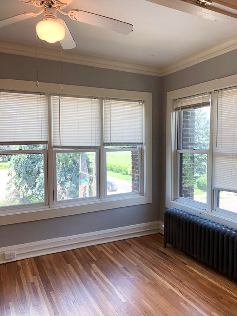 A room with a ceiling fan and a window with blinds.