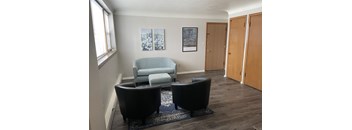A living room with a blue couch and two black chairs.
