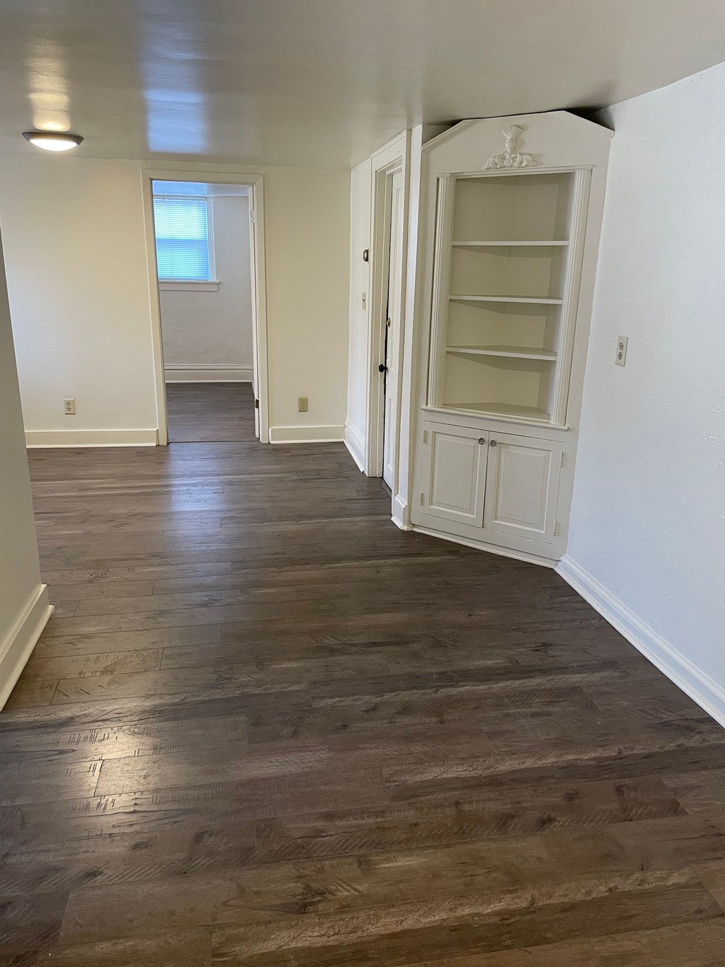 A long hallway with wood floors and white walls.