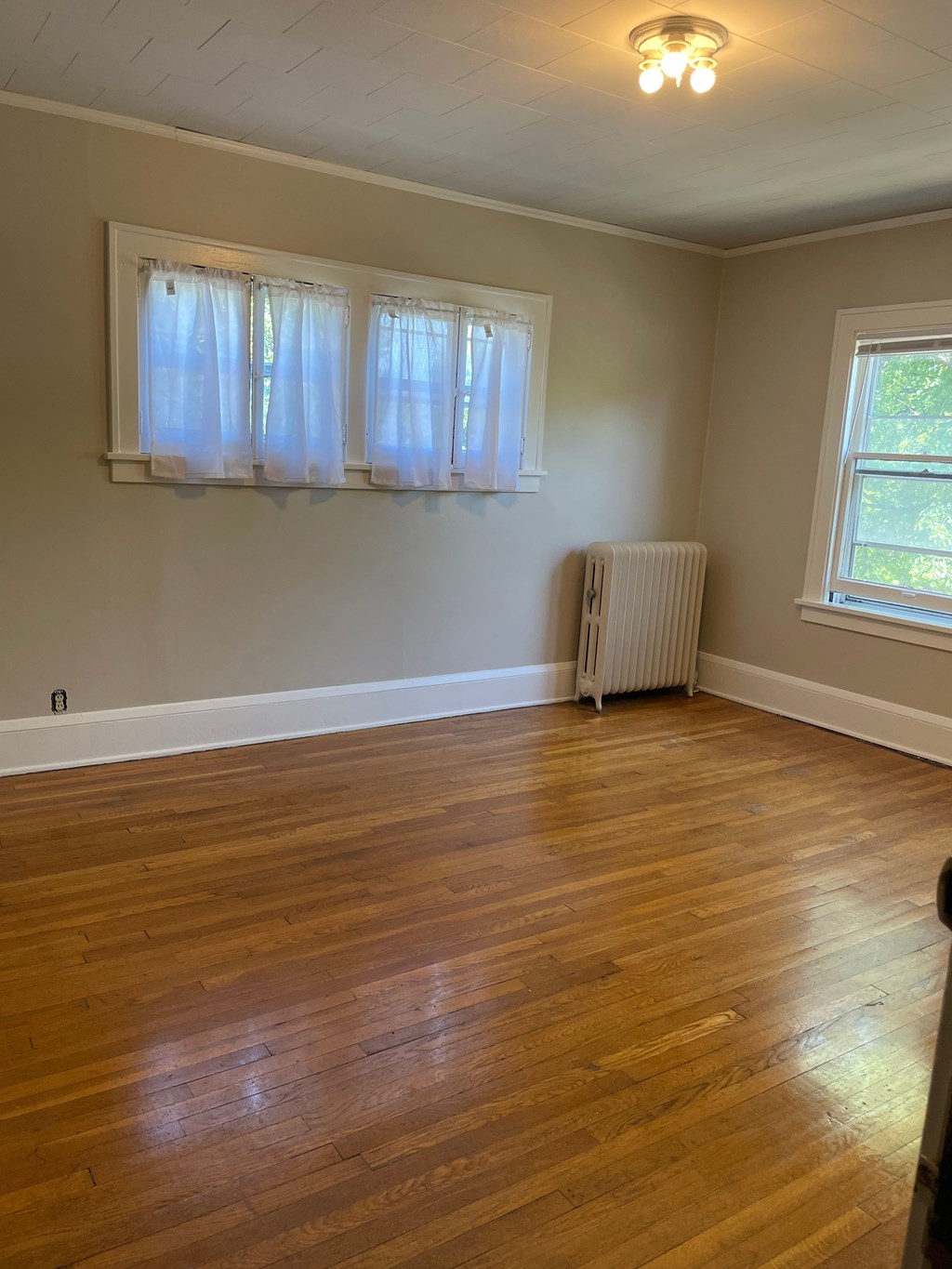A room with wooden floors and a window with curtains.