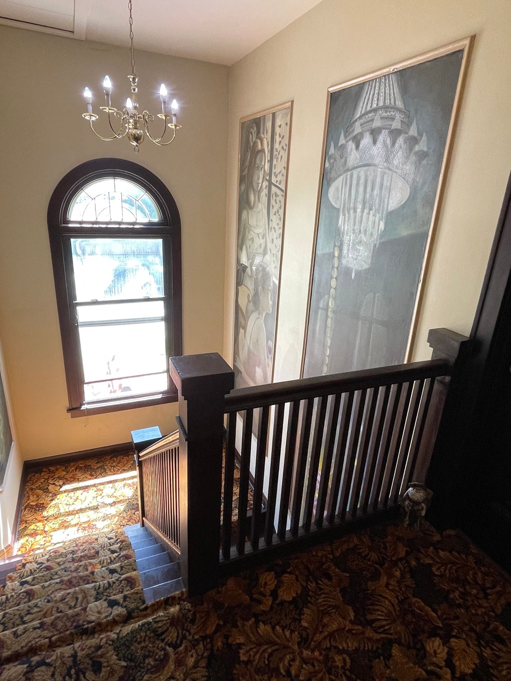 A staircase with a chandelier and a picture on the wall.