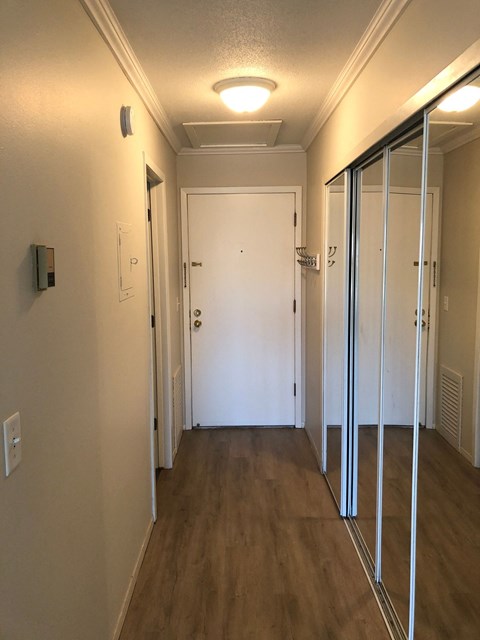A hallway with a white door and a white wall.