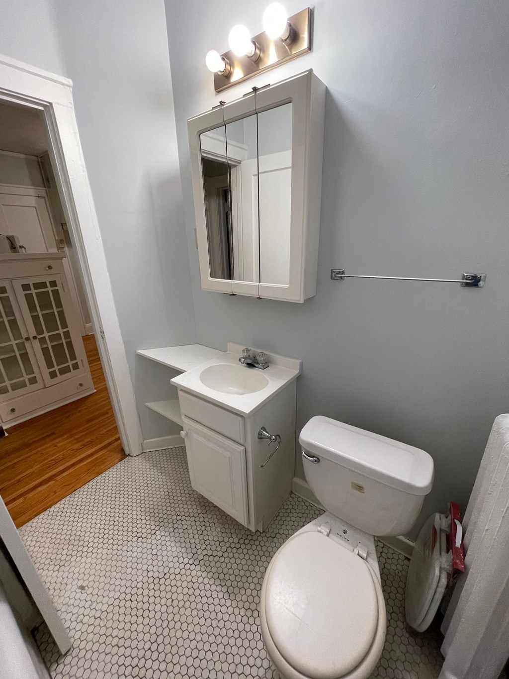 A white toilet with a white cabinet and mirror above it.