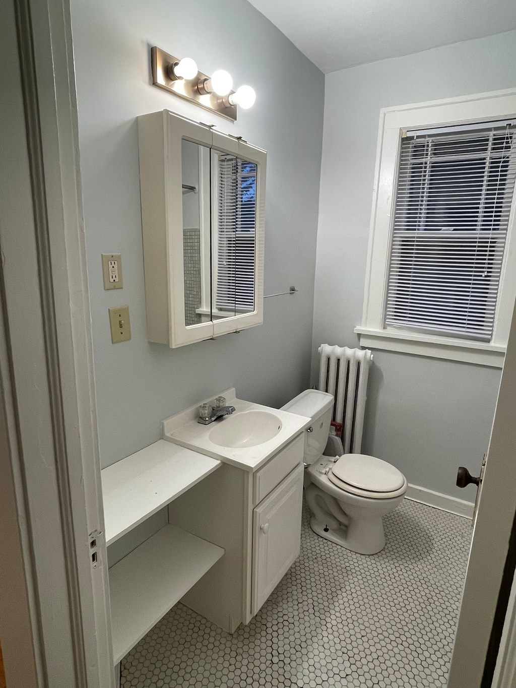 A white bathroom with a toilet, sink, and mirror.