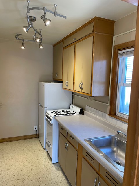 A kitchen with a white refrigerator and a sink.