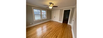 A room with a ceiling fan and wooden flooring.