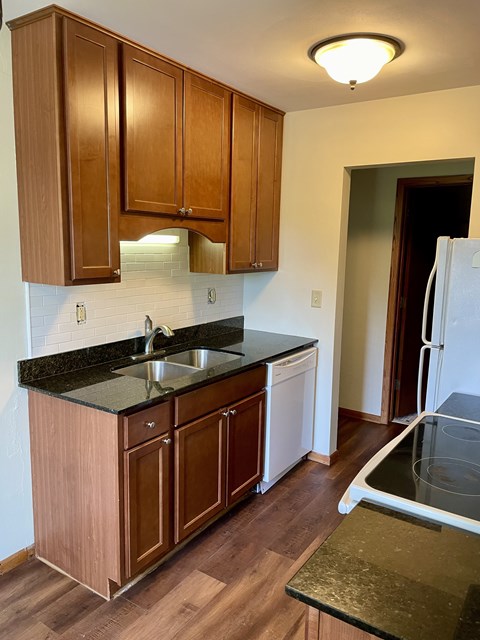 A kitchen with wooden cabinets and a black counter top.
