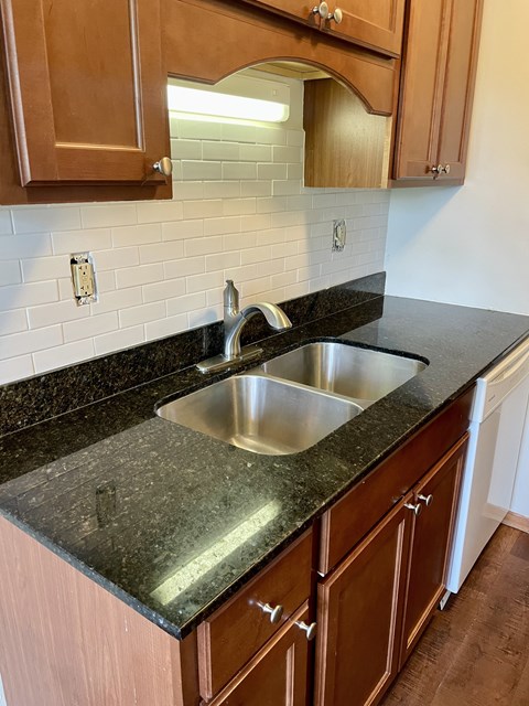 A kitchen with a sink and brown cabinets.