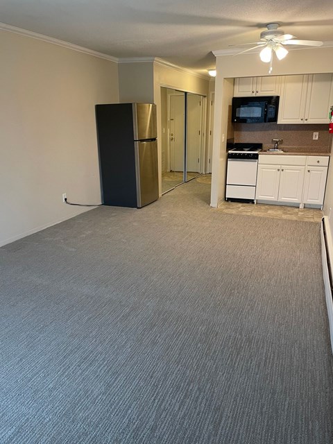 A black refrigerator in a kitchen with white cabinets and a microwave.