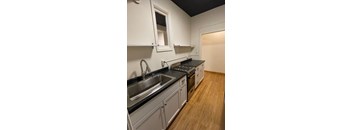A kitchen with wooden floors and a black counter top.