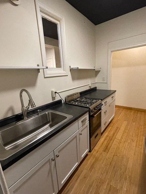A kitchen with wooden floors and a black counter top.