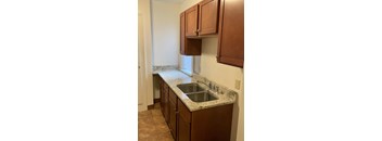 A kitchen with brown cabinets and a marble countertop.