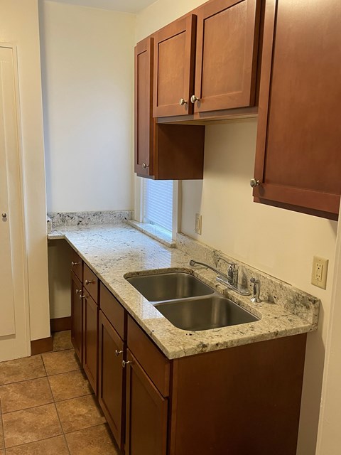 A kitchen with brown cabinets and a marble countertop.