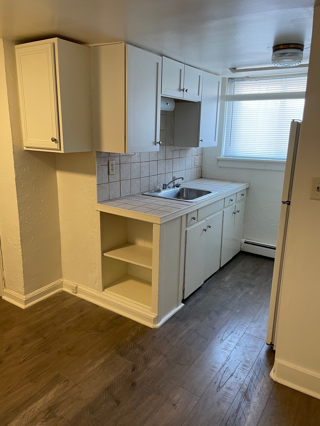 A kitchen with white cabinets and a wooden floor.