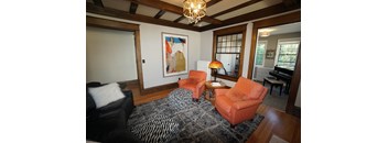 A living room with a black and white rug and orange chairs.