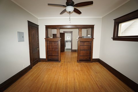 A room with a ceiling fan and wooden floors.