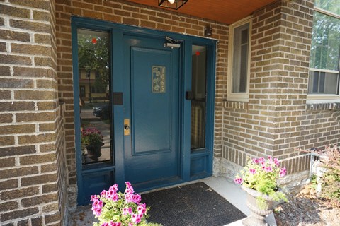 A blue door is on the left of a brick building.