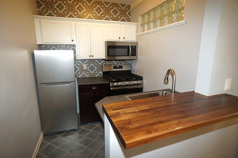 Updated kitchen with decorative tiled backsplash and floor, stainless steel fridge, gas stove and microwave.