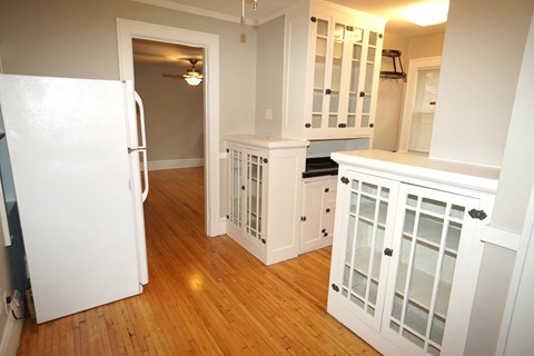 A kitchen with white cabinets and a white fridge.