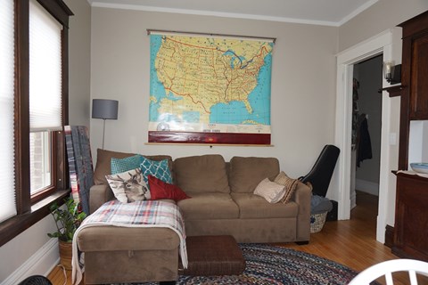A living room with a couch and a map of the United States on the wall.