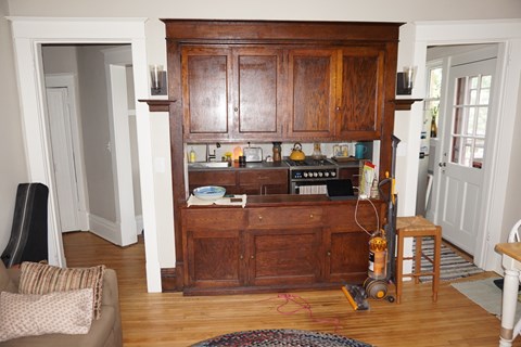A kitchen with a wooden cabinet and a chair.