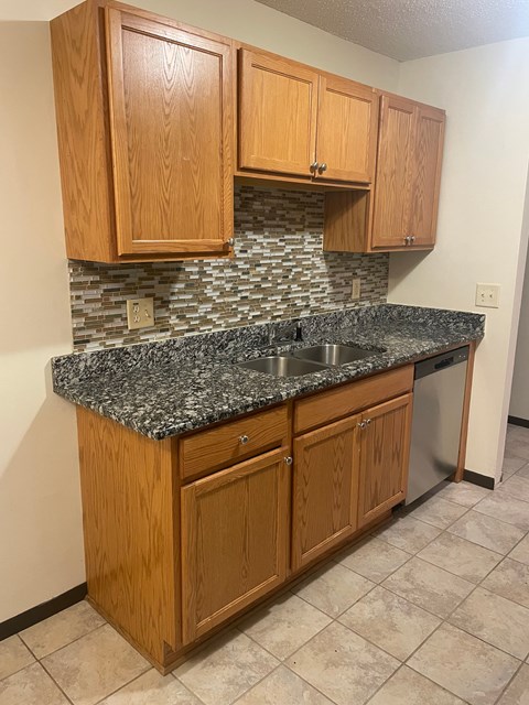 A kitchen with wooden cabinets and a granite countertop.