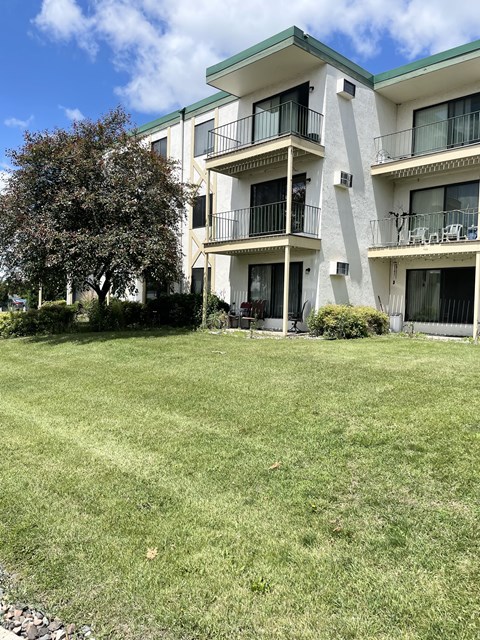 A large grassy area in front of a white apartment building.