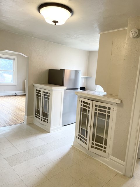 A kitchen with white cabinets and a black fridge.